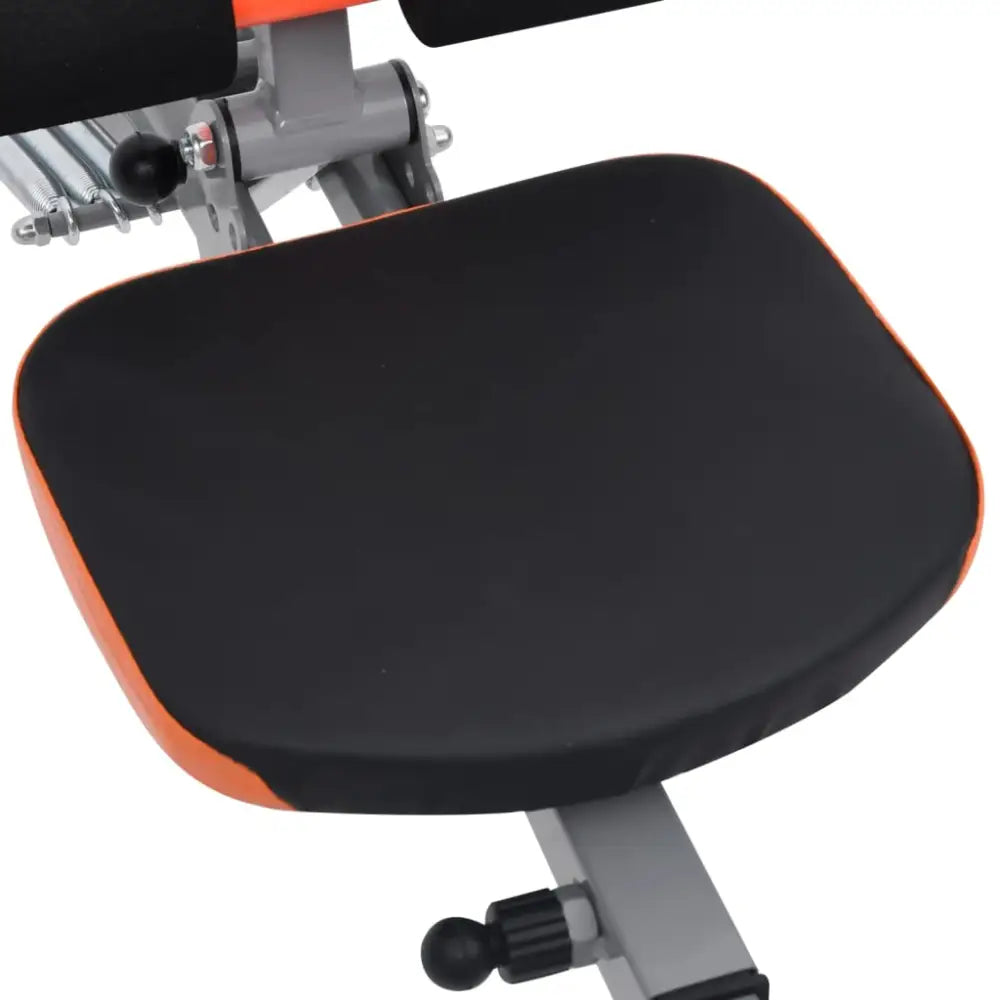 Gevoerd zitkussen met oranje bies bevestigd aan een frame van een fitnessapparaat.