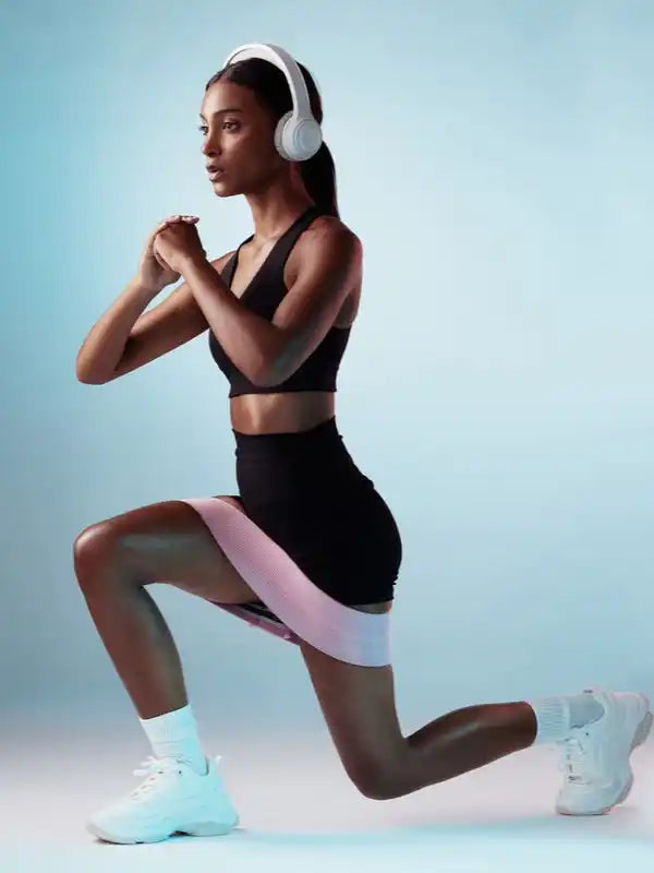 Vrouw die traint met een weerstandsband en koptelefoon.