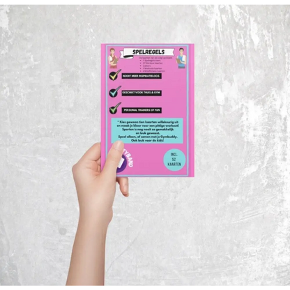 Roze flyer of kaart met bovenaan ’Spelregels’, vastgehouden door een hand tegen een lichte achtergrond.